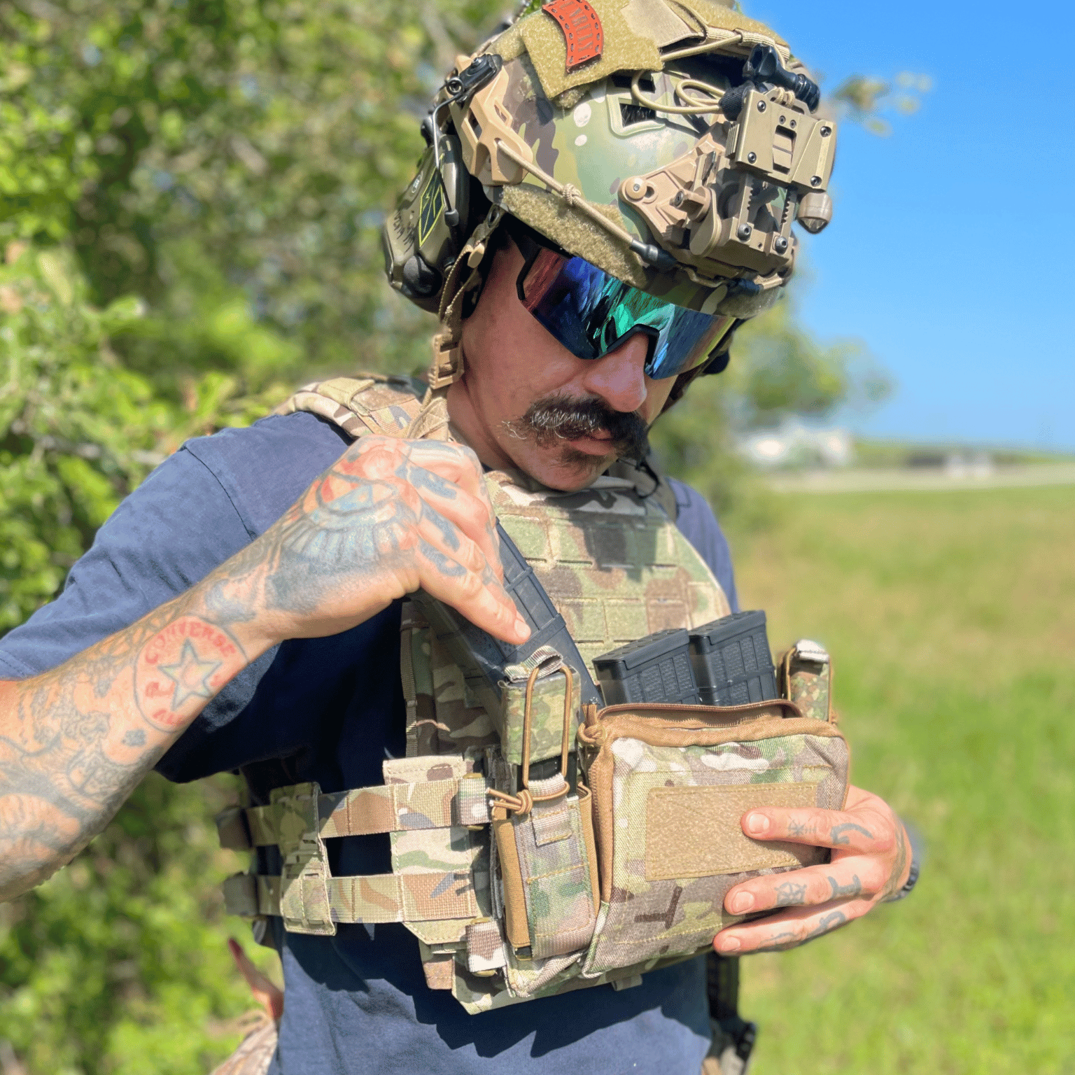 Person in tactical gear and helmet in multi-cam and camouflage pattern.