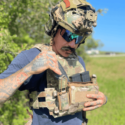 Person in tactical gear and helmet in multi-cam and camouflage pattern.