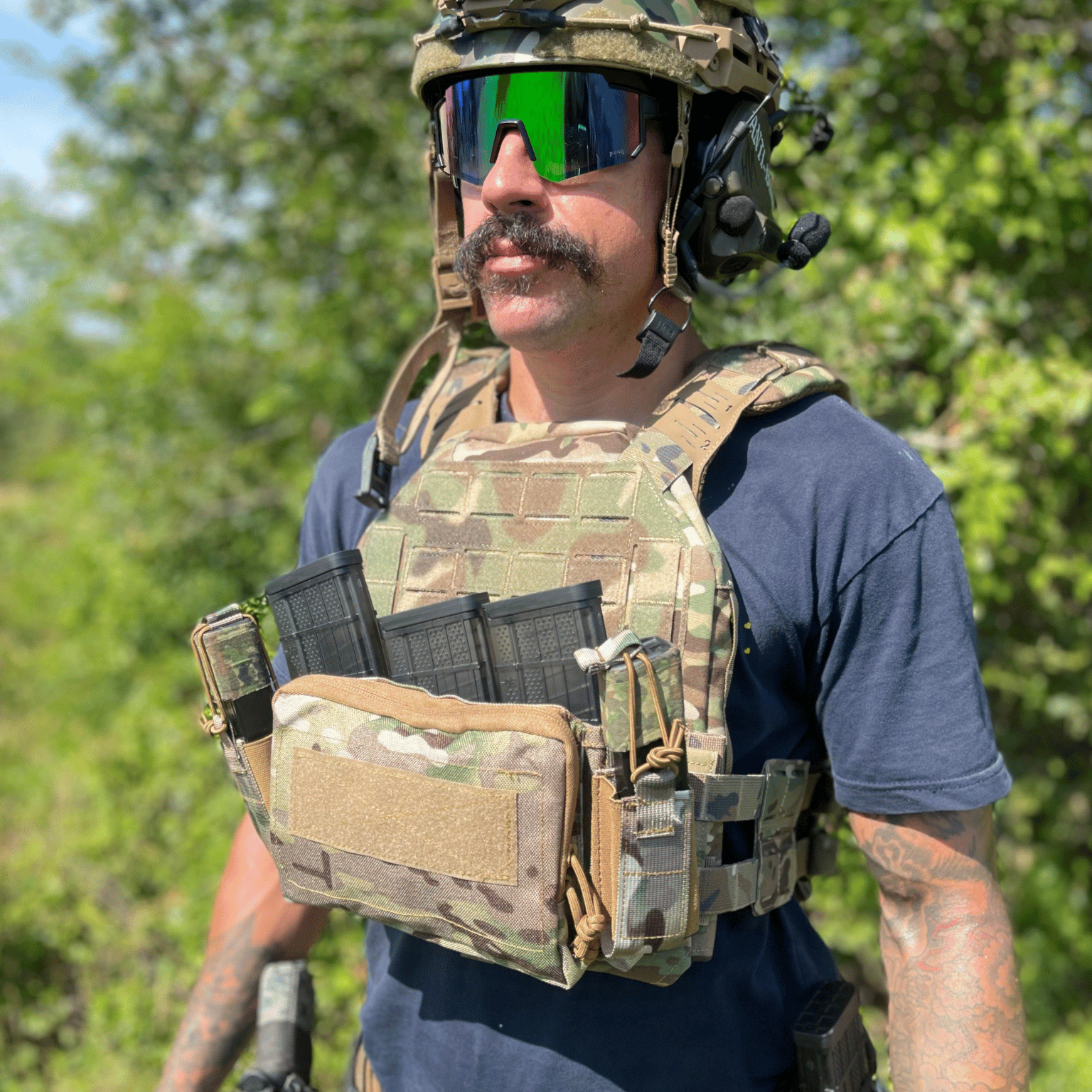 Person wearing tactical gear with a camouflage vest and helmet in an outdoor setting