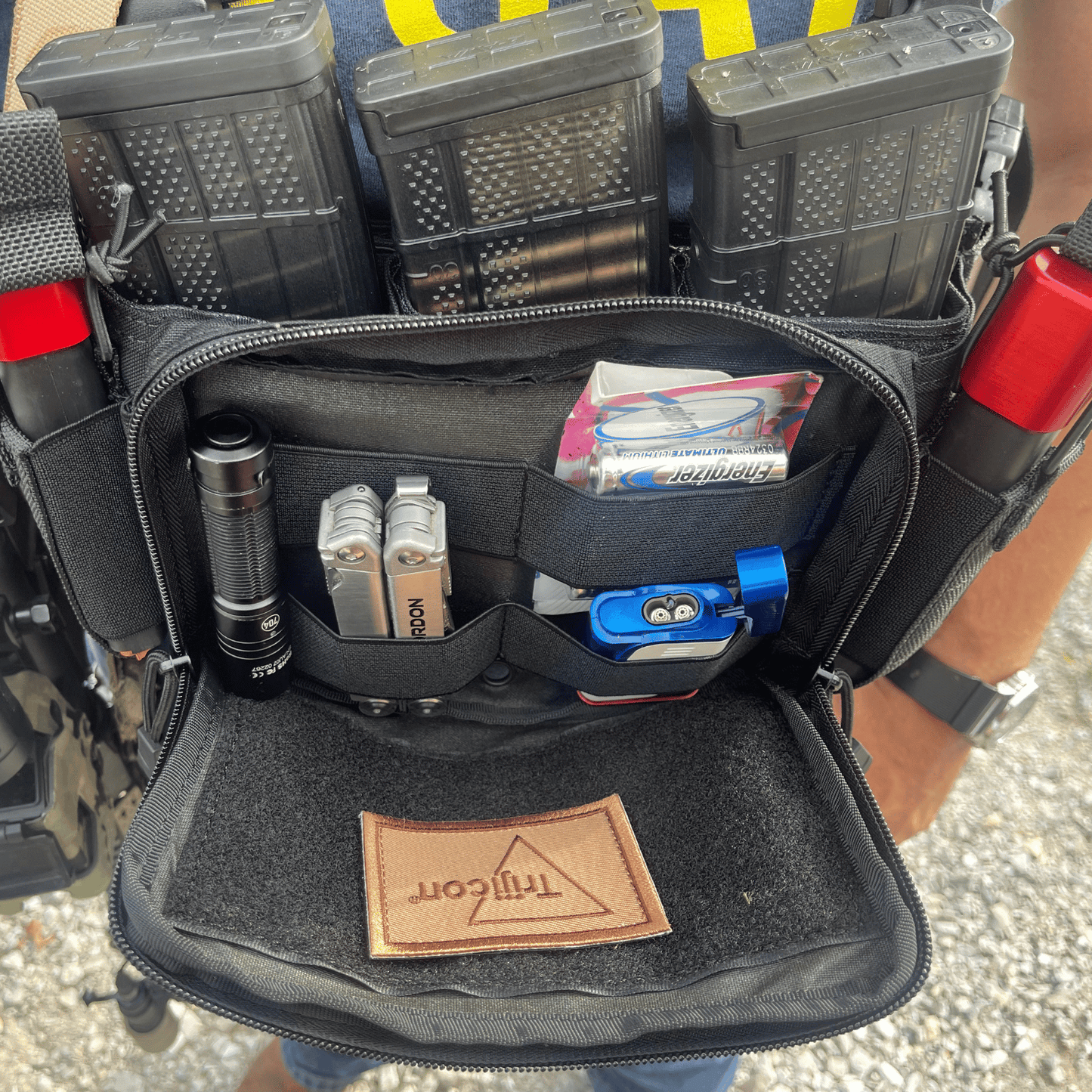 Black tactical pouch with various items including a flashlight and tools.
