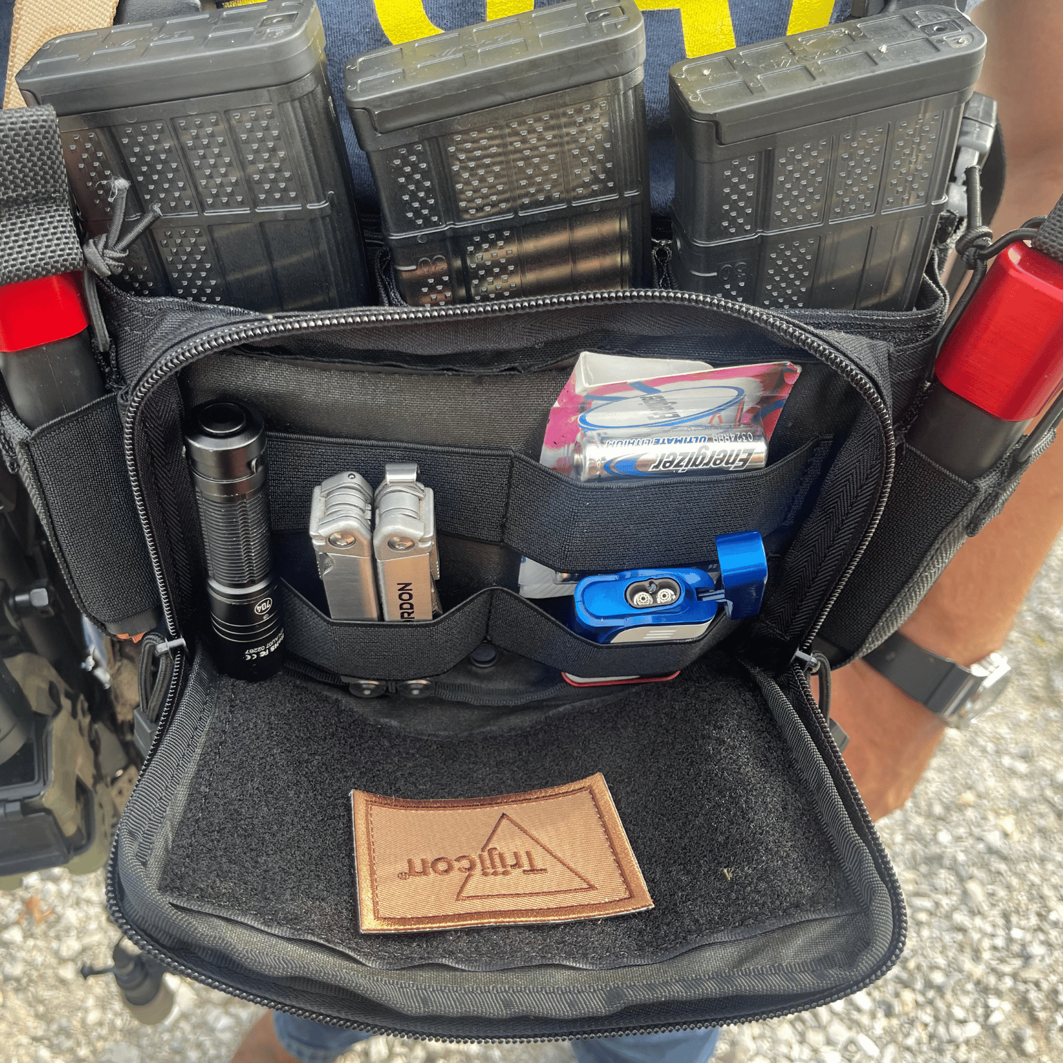 Black tactical pouch with various items including a flashlight and tools.
