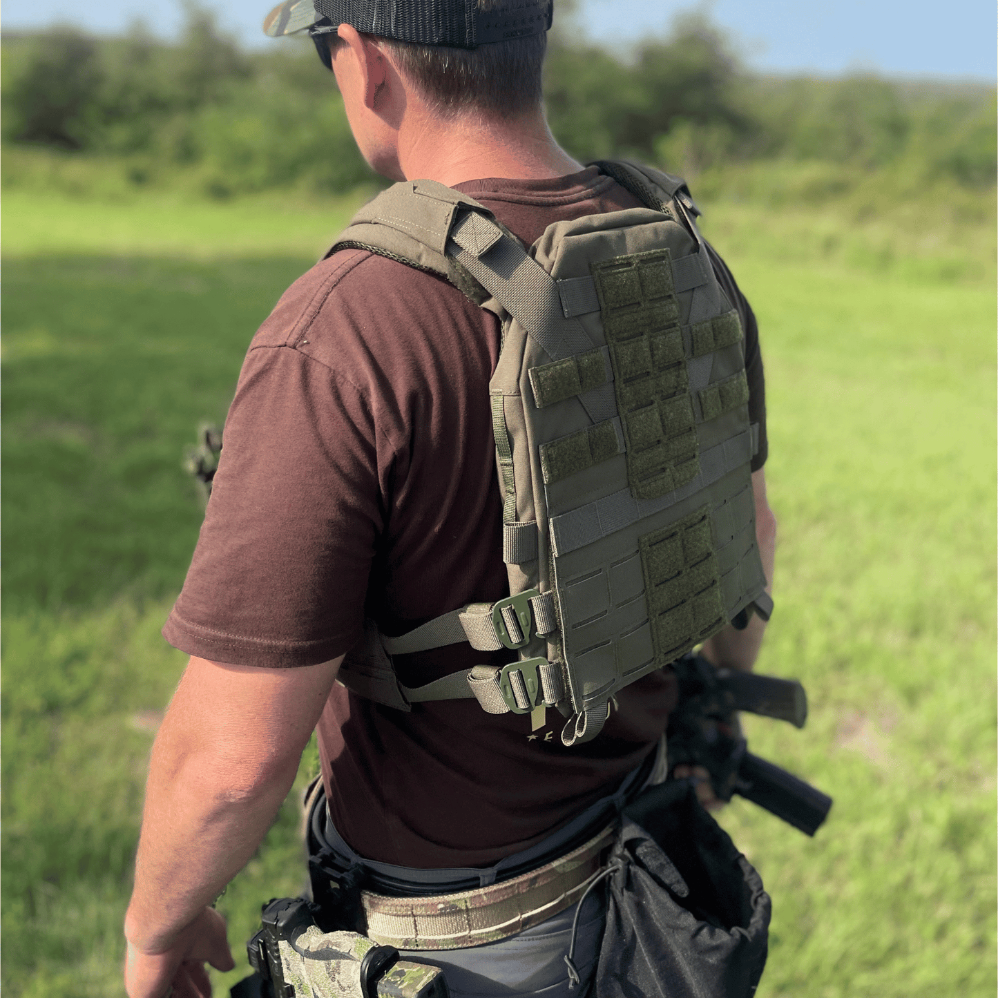 Rear side of person wearing a tactical vest in army green color.